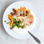 Bowl of homemade yogurt garnished with nectarines, mint, hemp seeds and almonds