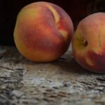 Ripe peaches in bowl on wooden background