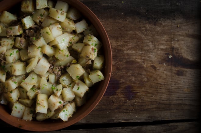 Roasted potatoes with liver in a terra cotta bowl on wooden background