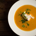 Sweet potato and poblano chile soup in white bowl on wooden background