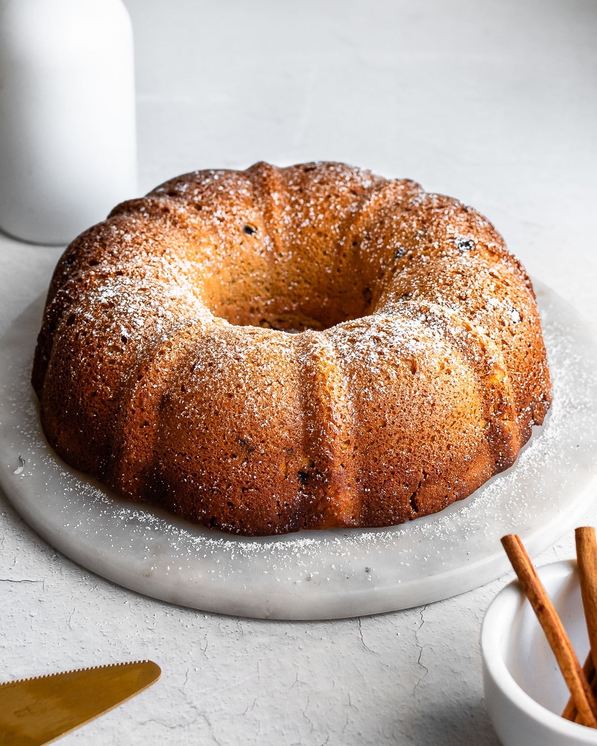 Election cake on a white marble cake stand, cinnamon sticks in foreground