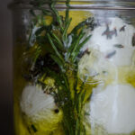 rosemary infused mozzarella balls in a jar with oil