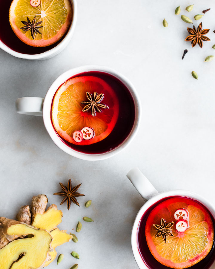 cranberry cider with orange slivers in 3 mugs
