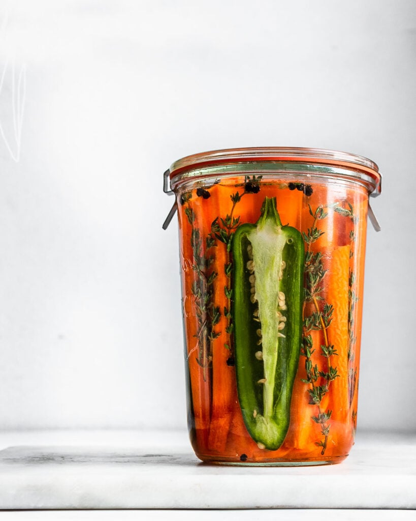 A jar fill with carrots, jalapeno and thyme ready for fermentation.