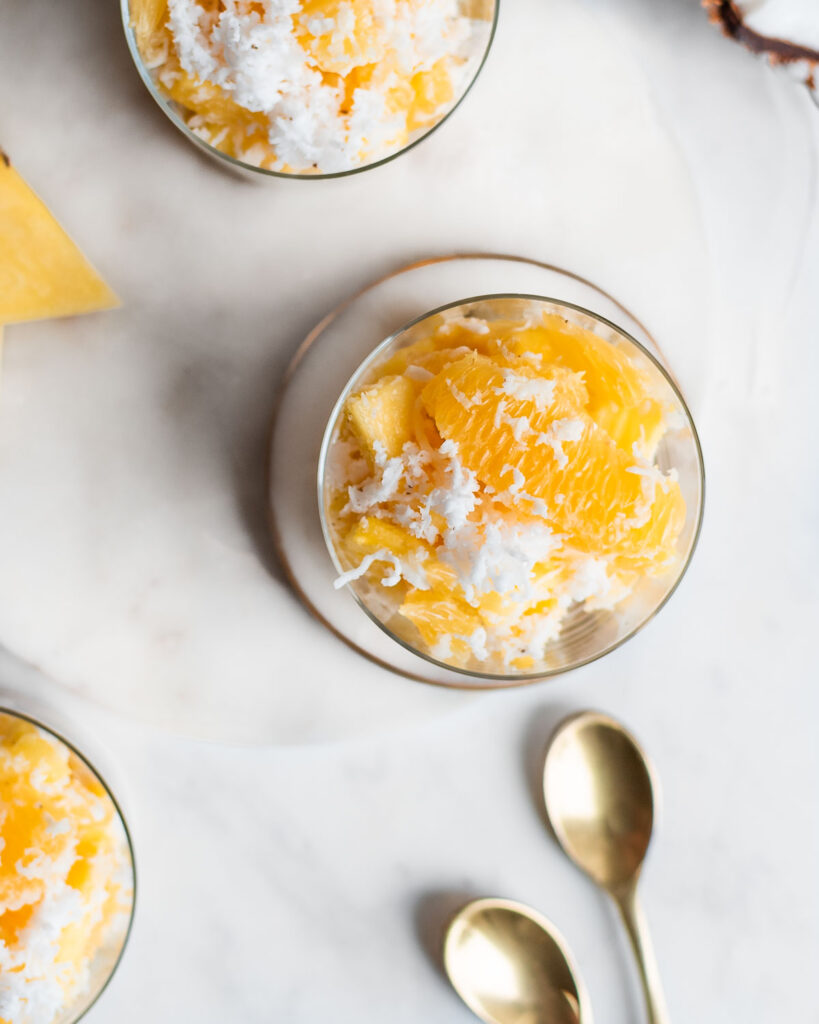 Three glass cups filled with ambrosia, garnished with fresh coconut
