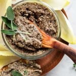 Muhsroom pate in a glass jar on a copper plate garnished with sage leaves and served with belgian endive