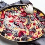 Flaugnarde with blueberries, strawberries, raspberries and mulberries, dusted with powdered sugar