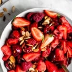 Red fruit salad with strawberries, raspberries, cherries and watermelon in a white bowl