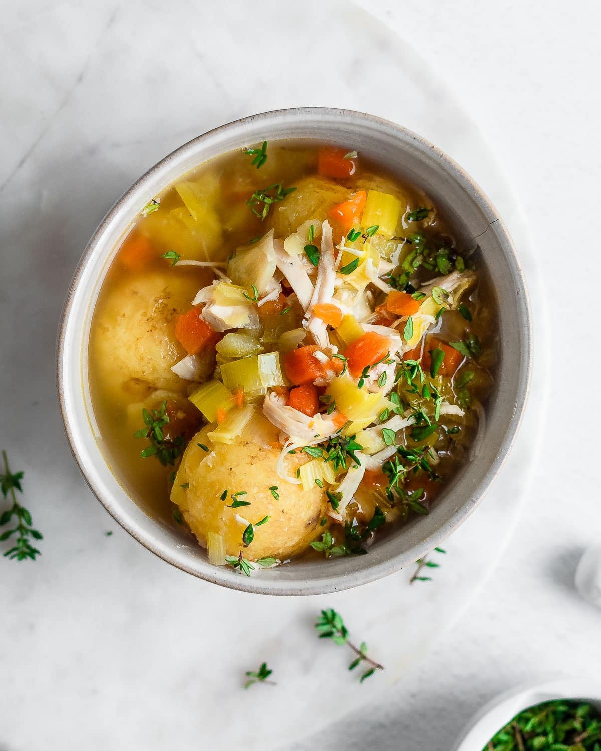 Slow cooker chicken soup in a bowl, garnished with fresh thyme