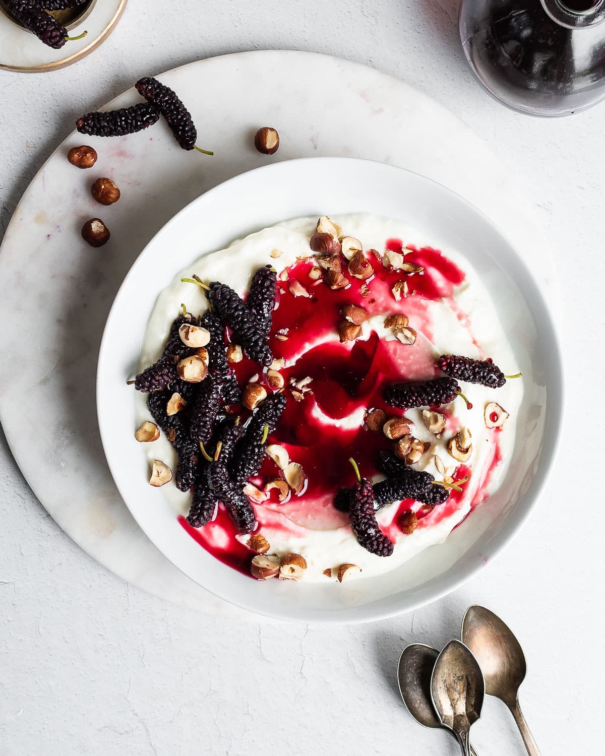 Bowl of yogurt topped with fresh mulberries and mulberry syrup.