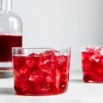Hibiscus kombucha in glasses with ice and a bottle of hibiscus kombucha in the background