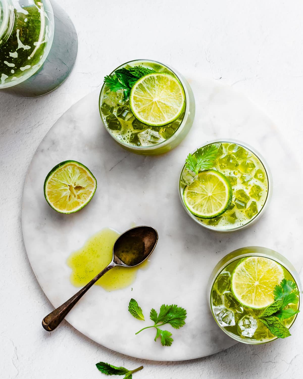 Herbal limeade in glasses with ice, garnished by lime and herbs