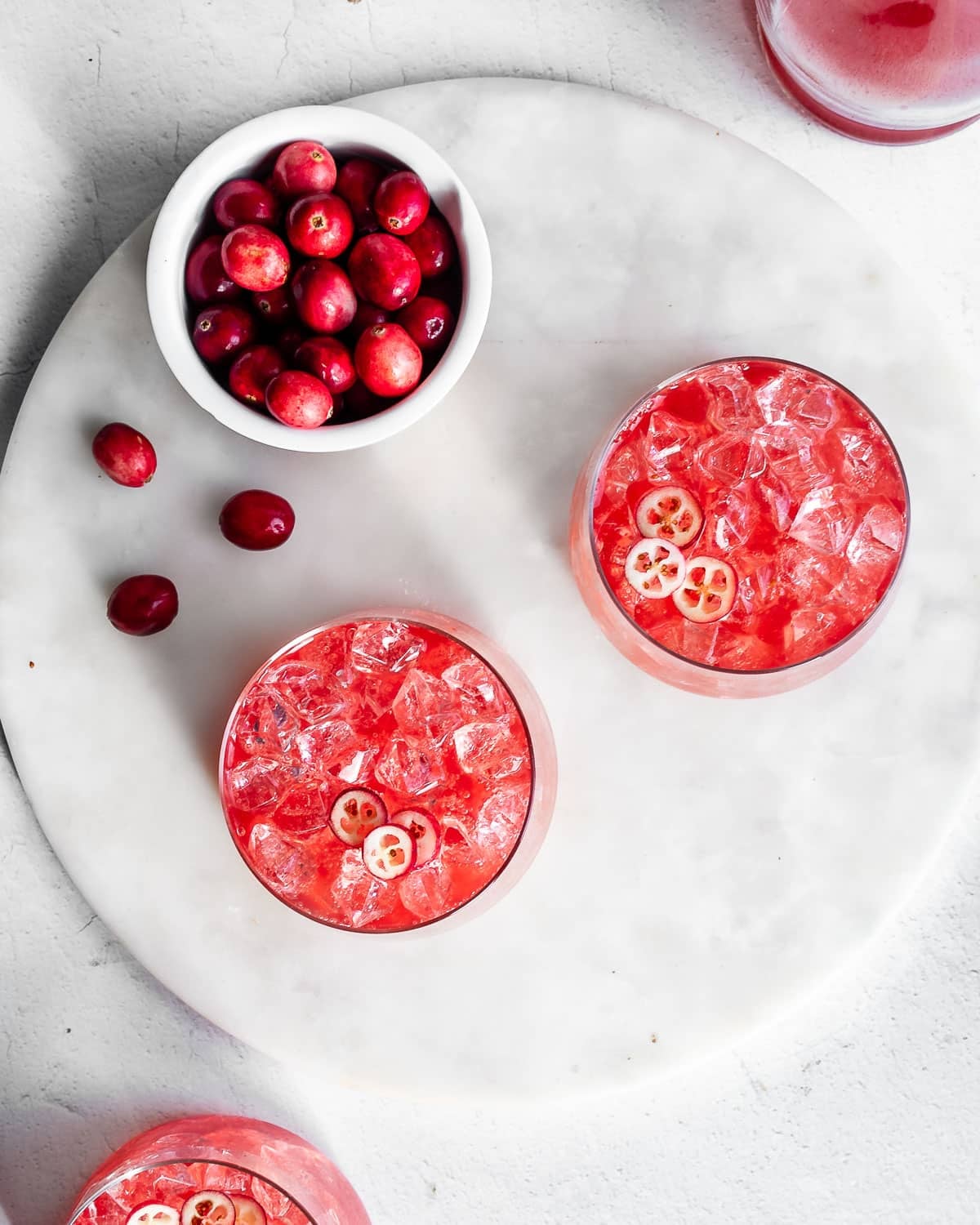 cranberry kvass in jars filled with ice, garnished with sliced cranberries