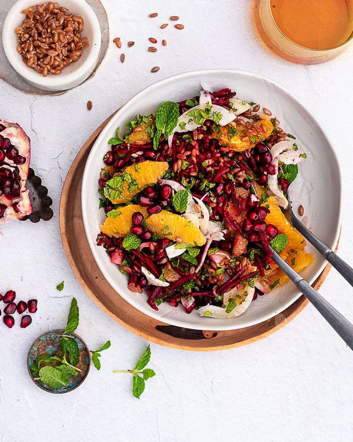 Winter Beet and Emmer Salad garnished with pomegranates, fennel and mint on a white bowl