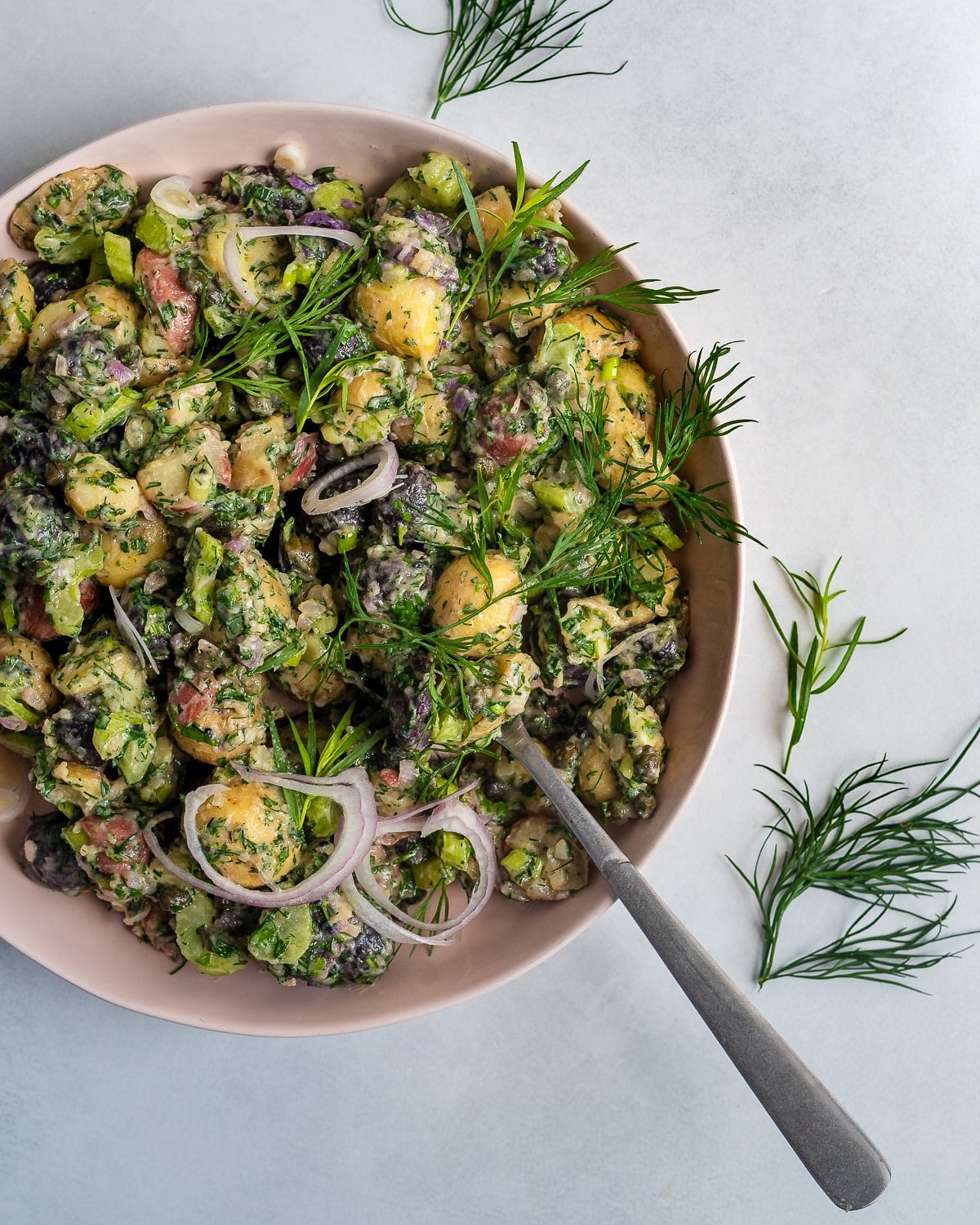 Herbed Potato Salad in a pink bowl garnished with dill and tarragon