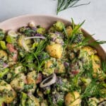 Herbed Potato Salad in a pink bowl garnished with dill and tarragon